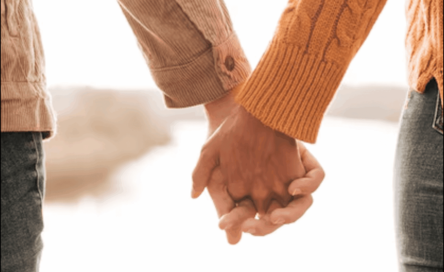 Closeup van een man en vrouw die elkaars hand vasthouden in zachte bruintinten